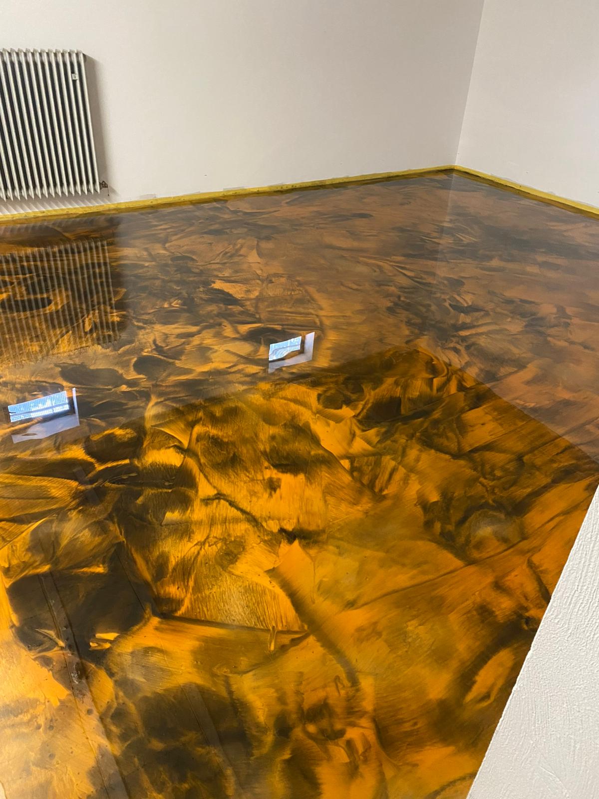 Goldfarbener Epoxidharzboden mit dunklen Strukturen und glänzender Oberfläche